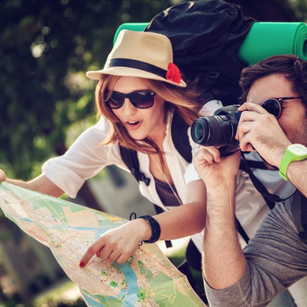 young male and female tourists using map and camera while sightseeing