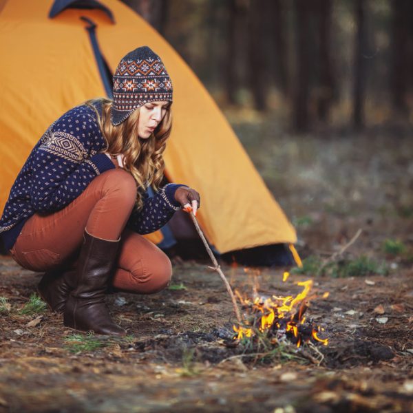 A woman building a fire while camping